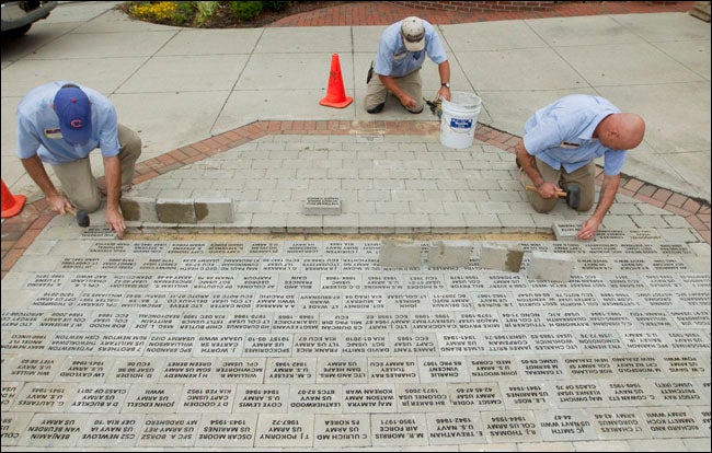 ECU Masonry workers John Phillips, James Boyd and Ron Causey install pavers at the Freedom Walk on campus.