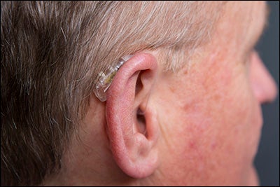 The SpeechEasy device is worn behind the ear with a small line that goes inside the ear.