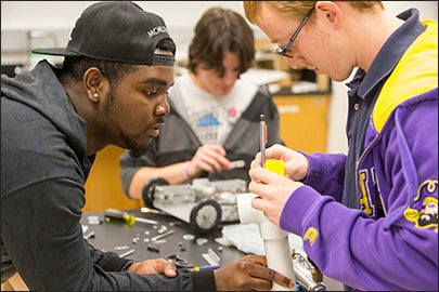 ECU students Brandon Gordon, left, and Patrick Williams work on a part while Walter Snead, background, works on the team's robot for a robotics class at ECU.