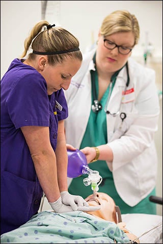 Nursing student C. Robinson applies pressure to the simulated patient, while medical student Laura Pekman assists with respiration.