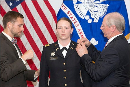 Ellen Johnson is pinned with gold second lieutenant bars by her father Robert Johnson Jr. and her brother Robert Johnson III.