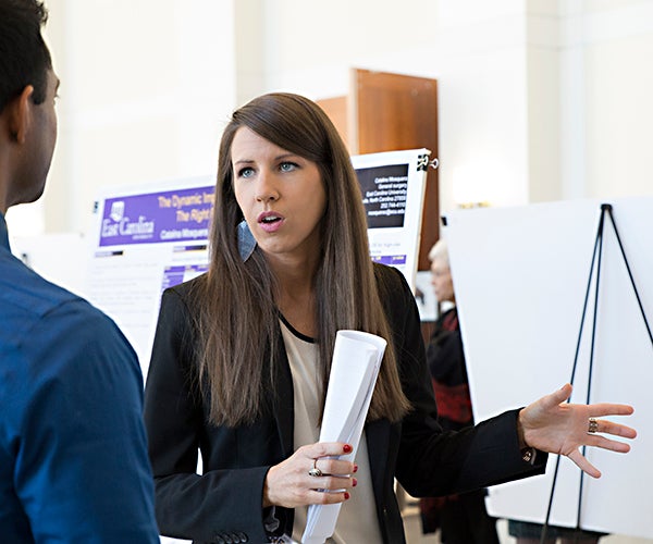 Dr. Heather Oxendine of the Brody’s Department of Psychiatry and Behavioral Medicine speaks with another symposium attendee about her poster presentation. 