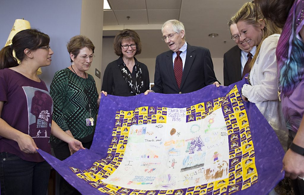 Students and staff from the College of Allied Health Sciences present members of the Scottish Rite organization with a quilt created by pediatric patients in ECU’s Speech-Language and Hearing Clinic. (Photos by Gretchen Baugh)