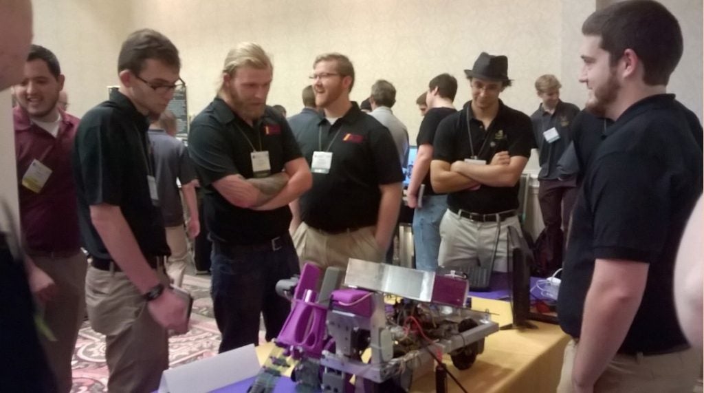 Team members from a competing team examine the ECU robot on display.