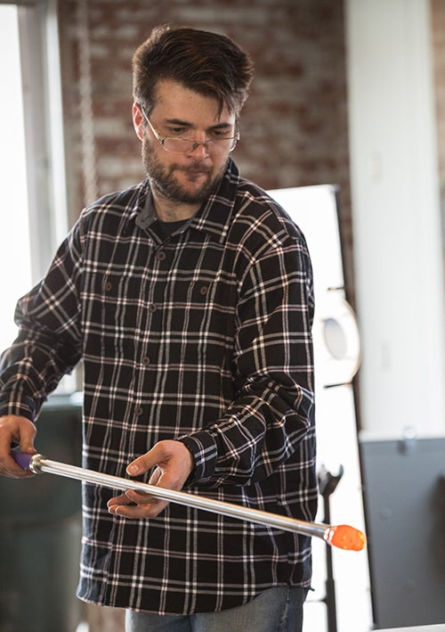 First-year graduate student Ronson Schultz rotates a fiery glass object.