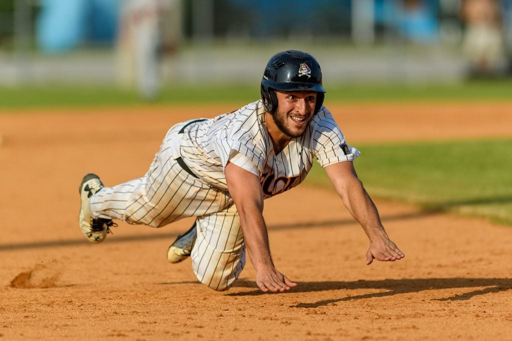 Catcher Jake Merzigian dive slides into third base against Elon.