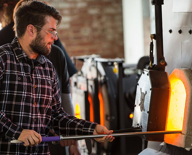 First-year graduate student Ronson Schultz rotates a fiery glass object.