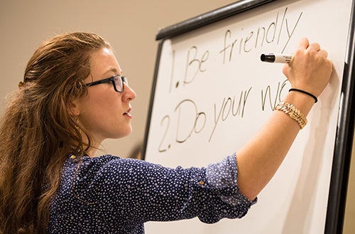 ECU junior Courtney Vitale writes expectations for the school year on a white board in collaboration with her virtual students.