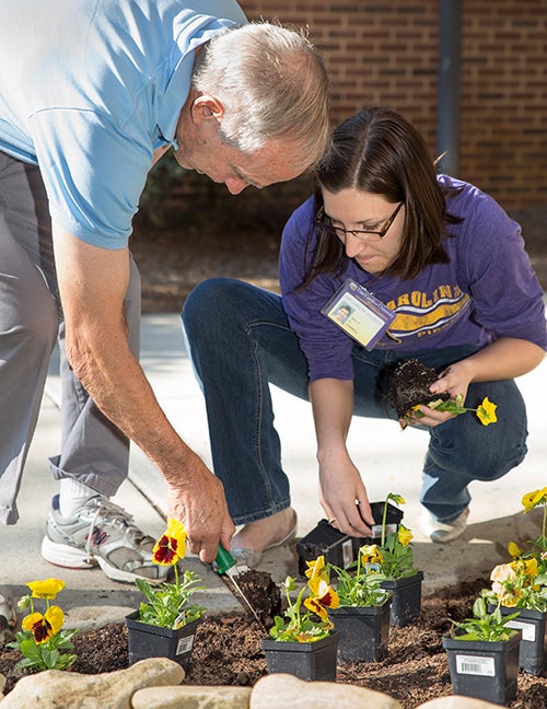 Graduate student Holly Gosnell helps patient Richard Brown plant pansies next to the entrance of the ECU Speech Language and Hearing Clinic.