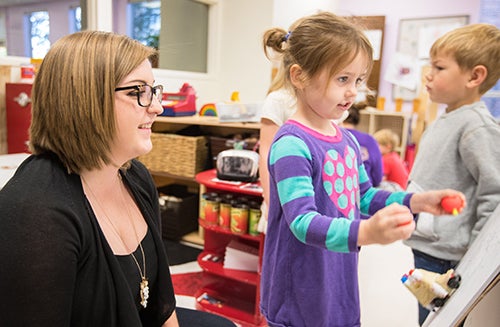 Student Zoe Vinogradov writes on a white board as Gavin Berrini waits his turn in the Nancy W. Darden Child Development Center. Their teacher, Amanda Blakley, received a statewide teaching award. 