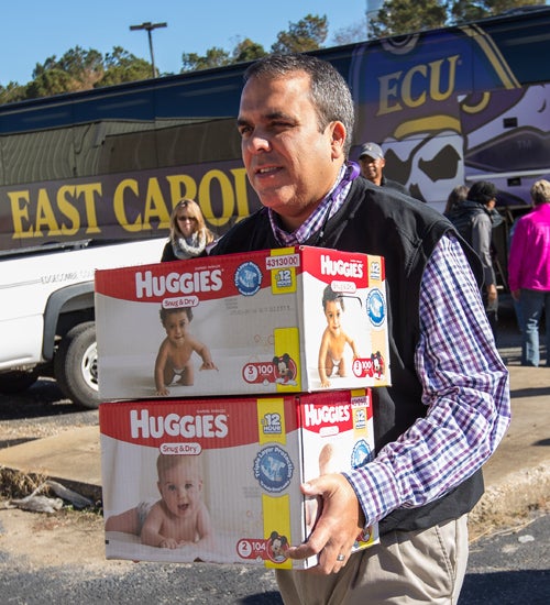 Chris Locklear, ECU vice provost for academic success, carries diapers into a recovery center in Princeville on Nov. 8.