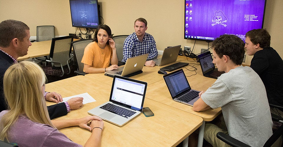 Darin Hooks, center, and his teammates discuss their project with professor Michael Harris during a class meeting.