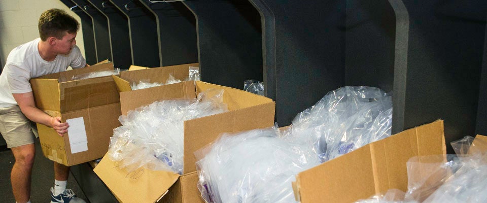 Logan Krause moves a box of giveaways for incoming students attending orientation.