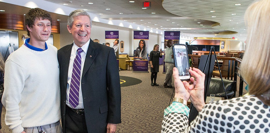 Chancellor Steve Ballard poses with James Regan, an ECU staff member and master’s student, as Nancy Ballard takes a photo at a reception in the club level of Dowdy-Ficklen Stadium on Tuesday.