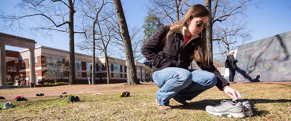 Sydney Parker reads the note attached to a pair of shoes during the S.H.O.E.S. Project. Each pair of shoes carried a story about one person’s challenges in order to spread the message that those who are suffering are not alone.