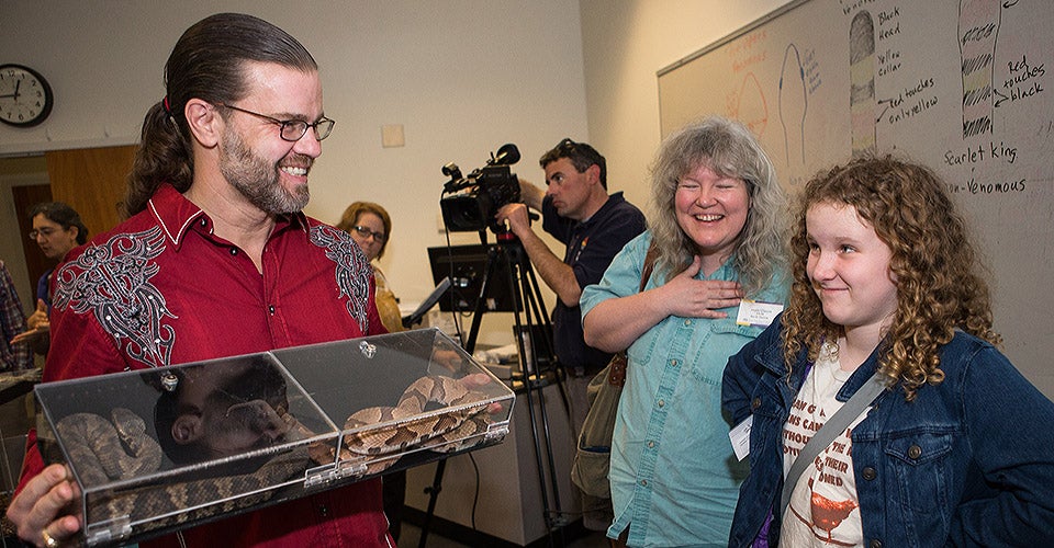 Dr. Sean Bush displays a copperhead and a cottonmouth at the live snake display in the Warren Life Sciences Building.