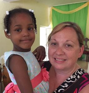 Michelle Kessler ’00 holds a little girl while visiting with residents in La Romana, Dominican Republic. (Contributed photo)