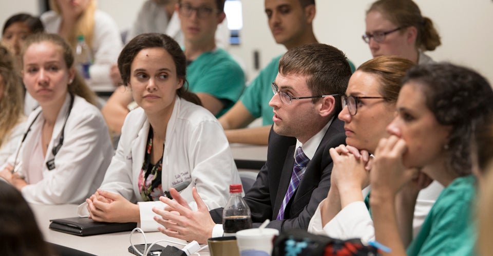 Fourth-year medical student Kevin Harris, center, asks a question after Corsa’s talk.