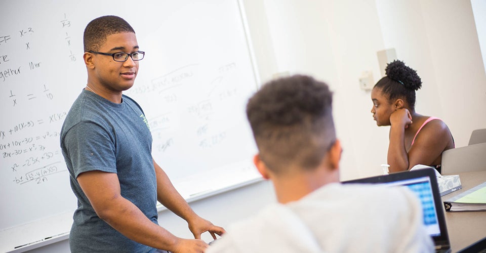 From left, Guiseppe Jeanty diagrams word problems with Shyheim Jones and Victoria McKinnon.