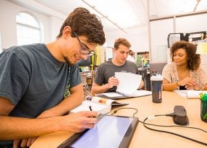 From left, Chris Garcia uses an electronic whiteboard while helping William Hicks and Precious White study vectors.