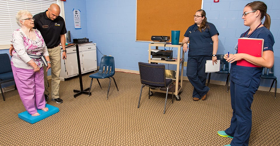 Brandon Kovash (left to right), Lindsey Layden and Megan Wittusen work with Betty Worthington during a fall prevention clinic in the rural Black Jack community.