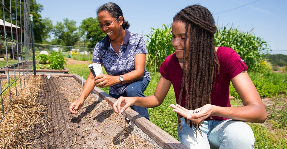 Jonelle Romero (right) and Making Pitt Fit Community Garden manager Joni Torres plant seeds on a summer morning.