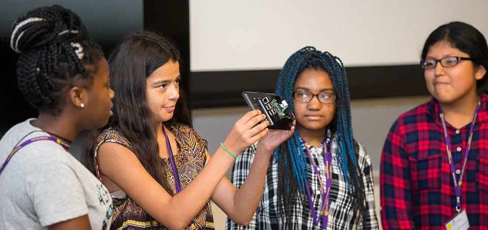 From left to right: Quisherra Tyson, Fatima Torres, Tiona Bailey, and Bryana Lopez show their parents a finished model of the Raspberry Pi mini computers that they built.