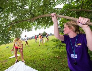 Teacher Lauren Brewington shakes a bush to collect items for further study.