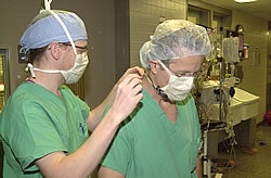 Tomas Mac Seain, left, an audio engineer with Internet broadcaster slp3D, wires a microphone on Dr. William Chapman in preparation for a gastric-bypass surgery Webcast. Photo by Cliff Hollis