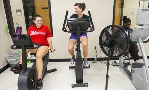 Left to right, Ashton Vann, mentor Laura Martin and Jeniya Roberson work out on recumbent bikes in Project Mentor.