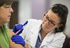 Pharmacy student Kyrstian Young, right, gives a flu shot to Renee Spain