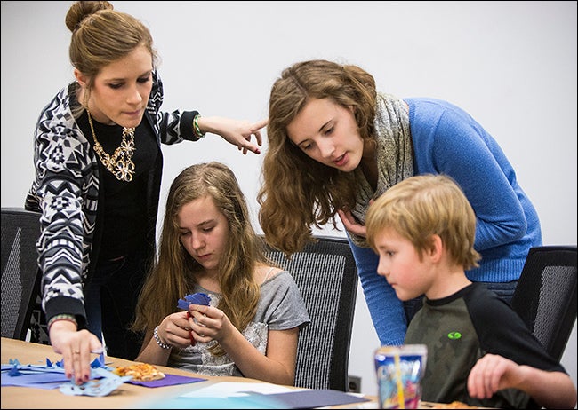 ECU students Emily Bosak, left, and Becca O'Hea, standing at right, assist Natilie Grey and Ryan Coan in their artwork.