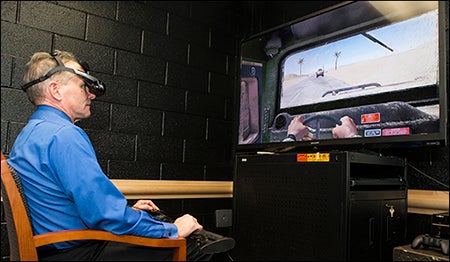 Jeff Zyburt wears virtual reality goggles while steering a vehicle in the opening of ECU's Center for Applied Psychophysiology.