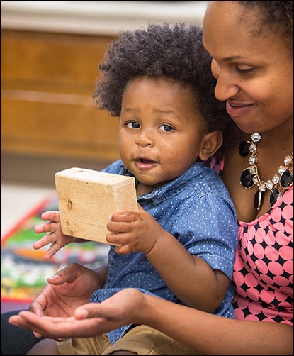 Toddler Kyrin Quinitchett enjoys playing with blocks with the assistance of Brandi Harris, lead teacher in the toddler classroom.