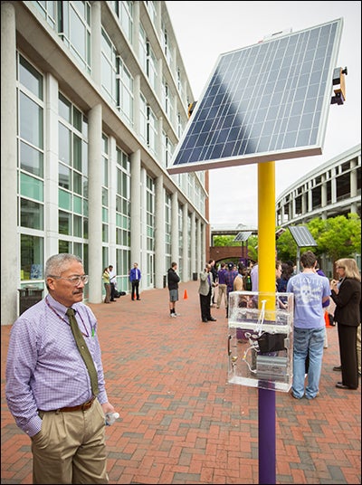 Dr. Robert Chin, a professor in technology systems, examines a solar charging station designed by one of the student groups.