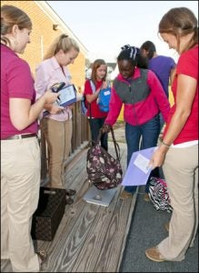 Erica Latham, age 12, places her backpack on the scale as (left to right) students Meredith Burke, Katie Apple, and Alison Bailey monitor the results.