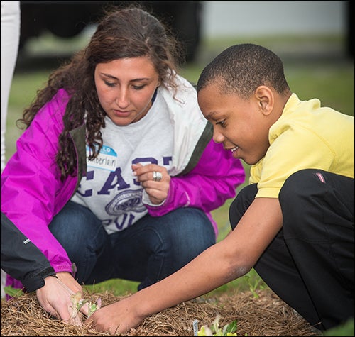 Kimberlain Childers, an ECU student volunteer, helps sixth-grader Jordan McKenzie re-plant a leafy green in the garden.