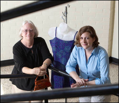 Catherine Billingsley, left, and Maria Modlin will display their art work in an exhibit beginning Tuesday at Laupus Library. Here, Modlin shows a top and shorts she made from fabric digitally-printed with microscopic images of ovarian cancer. Billingsley?s purse is made from images of her own hand x-ray. (Photo by Cliff Hollis)