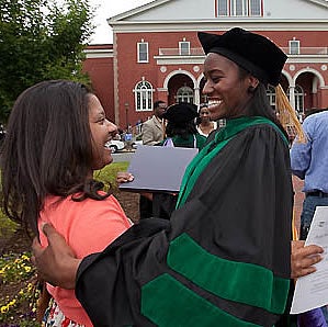 Dr. Tracy McLean, right, is congratulated by friend Bridget Hayes following the Brody School of Medicine convocation Friday, May 6. Photo by Cliff Hollis