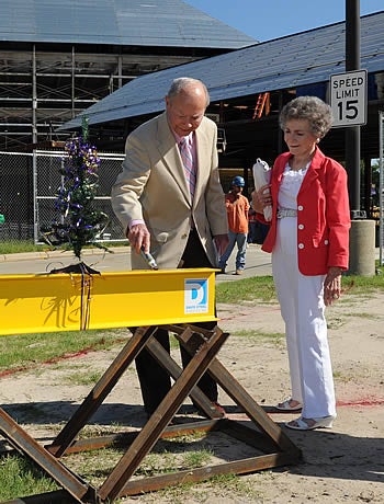 Dr. Ledyard Ross signs the topping out beam at the ECU School of Dental Medicine as his wife, Alta, looks on. Photo by Elbert Kennard