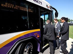 From left, students Micah Naylor, Chad Stinson and Bruce Townsend board a bus for the Brody Medical Sciences Building during the first day of orientation at the ECU School of Dental Medicine.