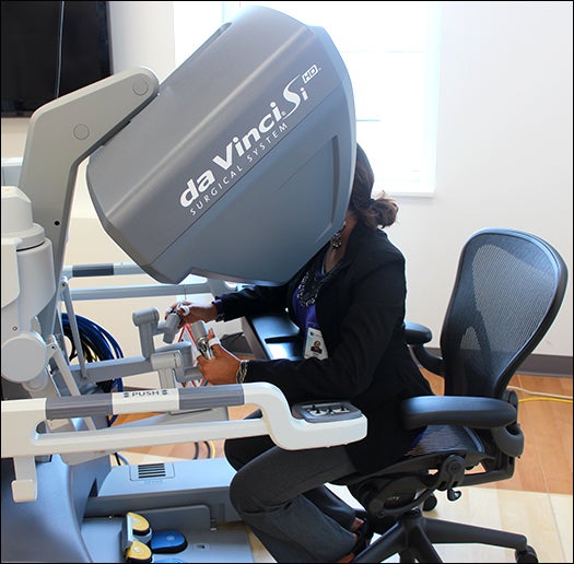 ECU Honors College student Aenia Amin demonstrates the daVinci Si robotic surgery system in the ECHI Robotics Lab.