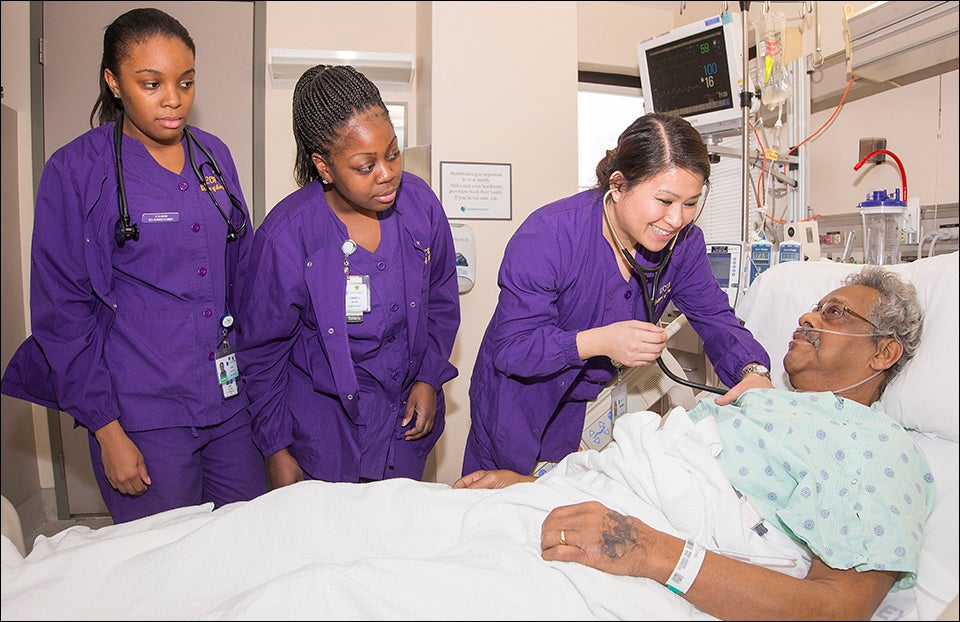 ECU nursing students, left to right, Staci Allgood, Chanté Brown and Kimberley Le learn while working with patient Roger Rice, a member's North Carolina’s fastest-growing population – those over 65 years of age.