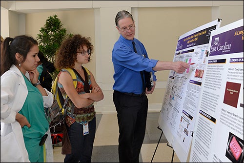 ECU pathologist Dr. Philip Boyer explains his poster presentation during Medical Education Day at the East Carolina Heart Institute.