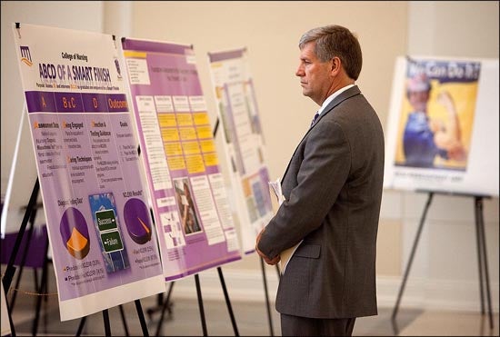 Assessment Day participants reviewed poster presentations set up outside the auditorium where Belle Wheelan spoke.