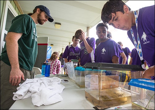 ECU doctoral student Scott Jones, left, shows students aquatic insects during an environmental symposium Monday at River Park North in Greenville.