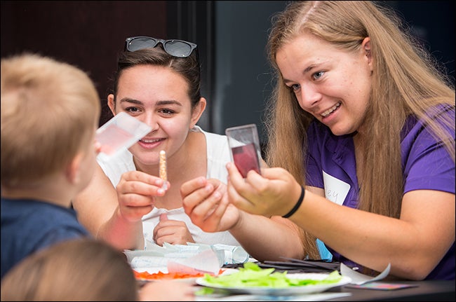 ECU Honors College students Caitlyn Palmer, left, and Ashley Weingartz help students make stained glass from paper as part of annual Service Day activities.