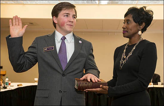 Vice Chancellor for Student Affairs Virginia Hardy, right, holds the Bible while new SGA President Jake Srednicki is sworn in at the Board of Trustees meeting.