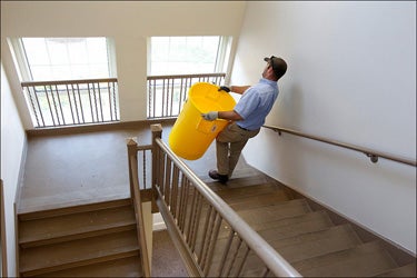 Jay Wainwright of ECU Facilities Services works to remove water captured from leaks in Spilman.