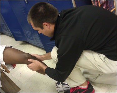 ECU graduate assistant Jeff Barfield examines an athlete's knee before play. Barfield is a certified athletic trainer working with athletes in Pitt County Schools. (Contributed photo)